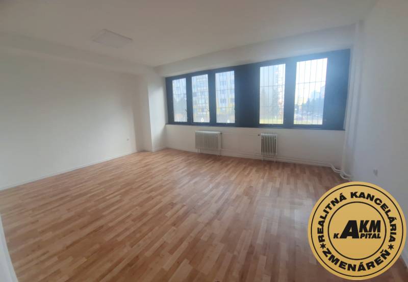 Innenraum eines Büros mit Holzboden und großen Fenstern.