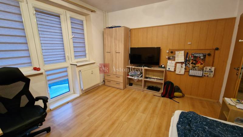 Ein Zimmer in einer 3-Zimmer-Wohnung mit Holzboden, Fernseher und Sessel.