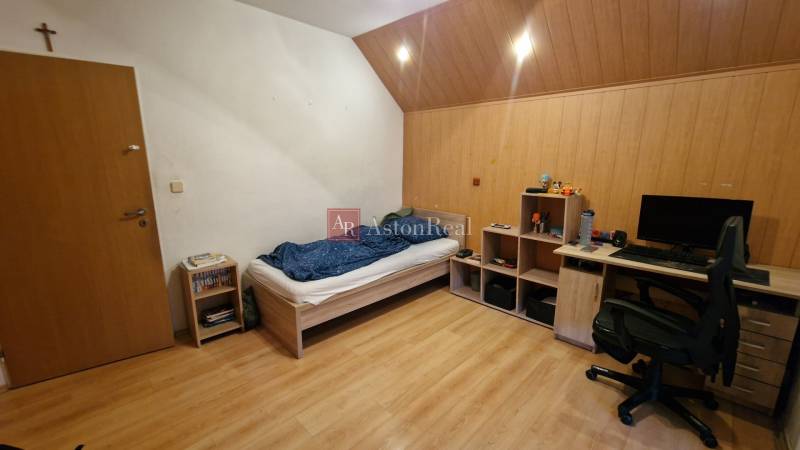 Ein Zimmer in einer 3-Zimmer-Wohnung mit einem Bett, einem Schreibtisch und einem Boden mit Holzdekor.