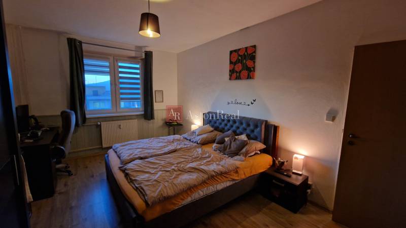 Schlafzimmer mit Doppelbett, Schreibtisch und Boden mit Holzdekor in einer 3-Zimmer-Wohnung.