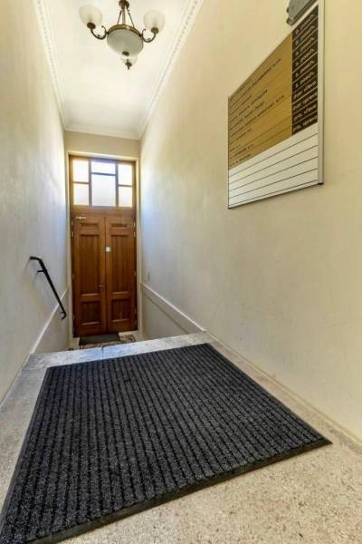 Eine enge Treppe mit einer Leiter und einer Lampe führt zu einer Holztür. Büros.