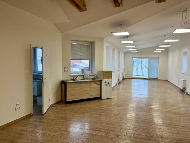 Büros mit Holzboden, großen Fenstern und einer Kochnische.