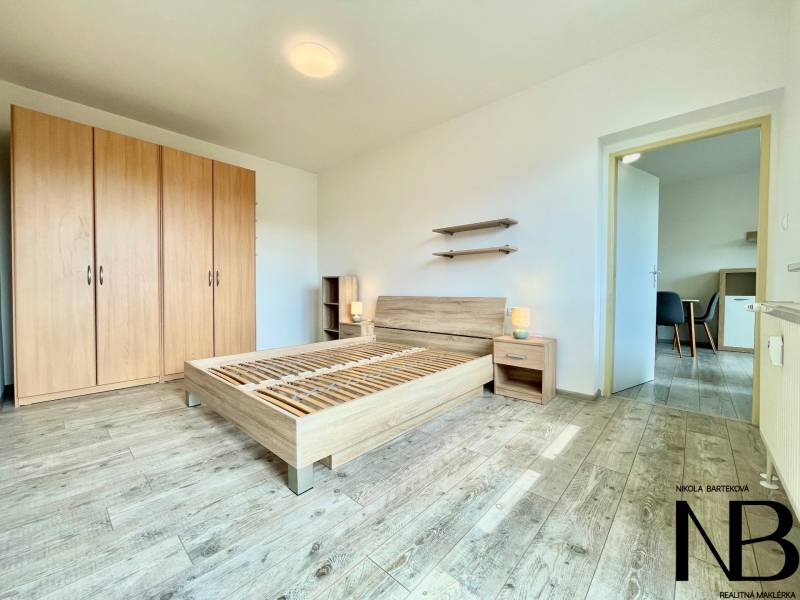 Helles Schlafzimmer mit Holzboden, Bett und Schrank in einer 2-Zimmer-Wohnung in der Východná-Straße.