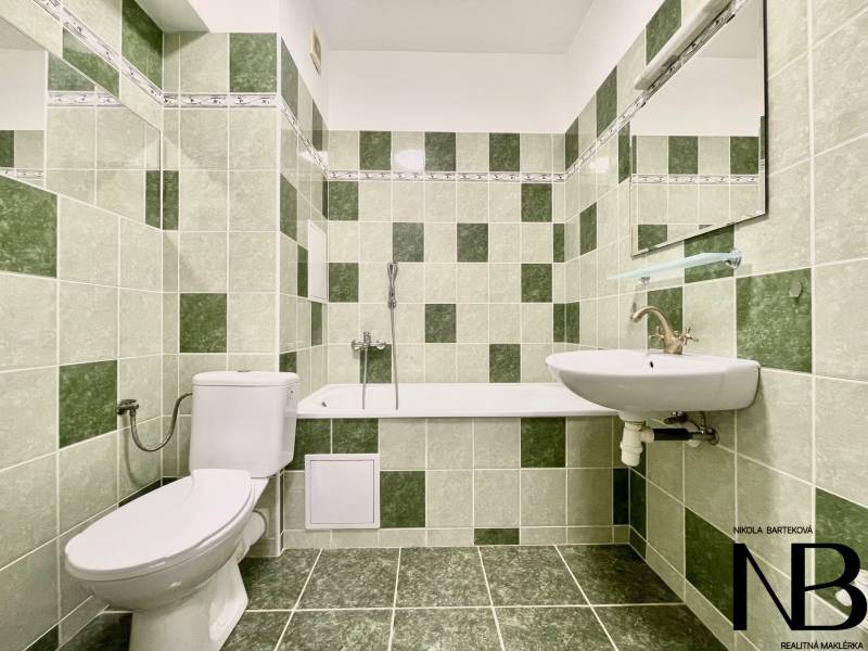Badezimmer in der Východná-Straße mit grünen Fliesen, Badewanne, Waschbecken und Toilette in einer 2-Zimmer-Wohnung.