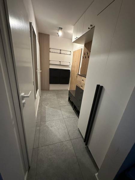 Flur in einer 2-Zimmer-Wohnung mit Fliesen, Schränken und Holzvertäfelungen.