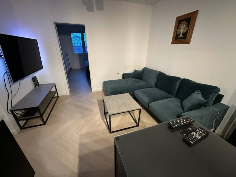 Wohnzimmer in einer Zweizimmerwohnung mit Holzboden und bequemer Couch.