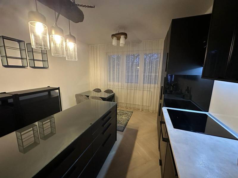 Küche in einer 2-Zimmer-Wohnung mit Glasleuchten und einem Boden in Holzoptik.