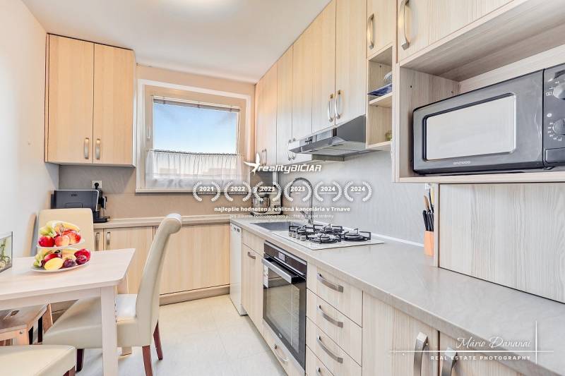 Küche in einer 4-Zimmer-Wohnung mit Obst auf dem Tisch und eingebauten Geräten.