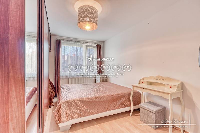 Schlafzimmer in einer 4-Zimmer-Wohnung mit Bett, Schreibtisch und Boden in Holzoptik.