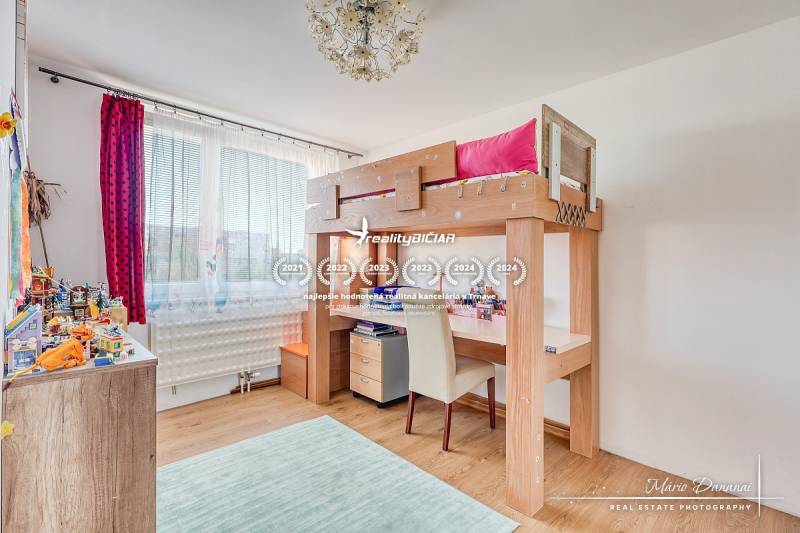 Kinderzimmer mit einem Hochbett, einem Boden in Holzoptik und Spielzeug auf den Regalen.