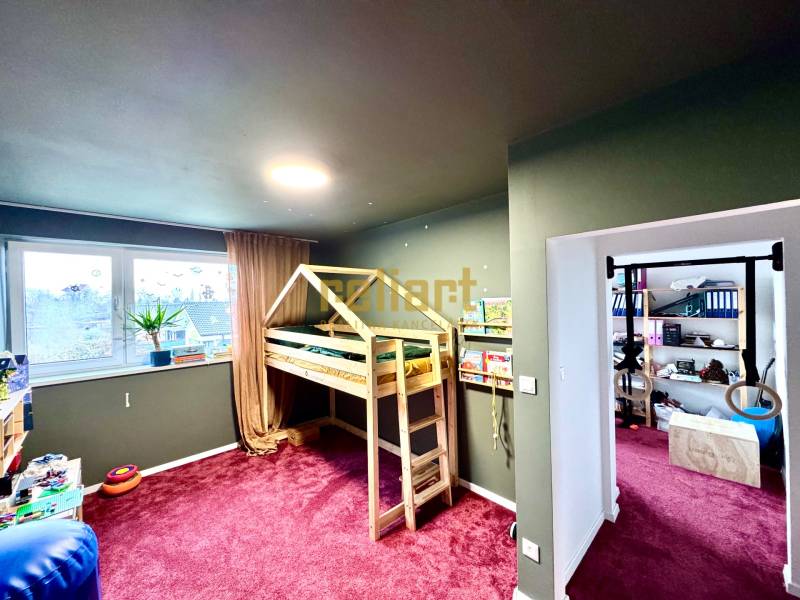 Kinderzimmer in einem Einfamilienhaus mit einem Holzbett und einem bordeauxfarbenen Teppich.