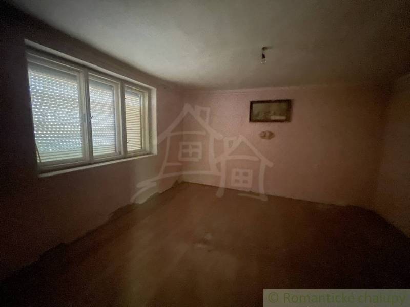 Ein leerer Raum in einem Einfamilienhaus mit Holzboden und einem großen Fenster.