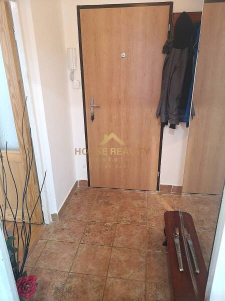 Eingangsbereich einer Zweizimmerwohnung mit Keramikboden und Jacken an der Garderobe.