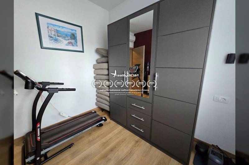 Laufband, Schrank mit Spiegel und Boden mit Holzdekor in einer Ferienwohnung.