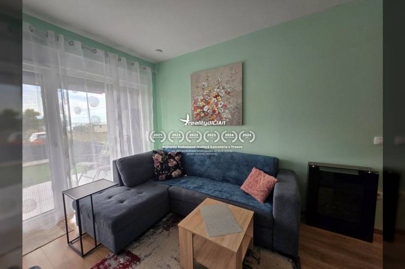 Wohnzimmer einer Ferienwohnung mit Sofa, Tisch, Dekorationen und Fenster mit Aussicht.