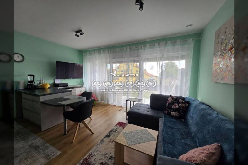 Wohnzimmer in einem Ferienapartment mit Holzboden, Sofa und Fernseher.