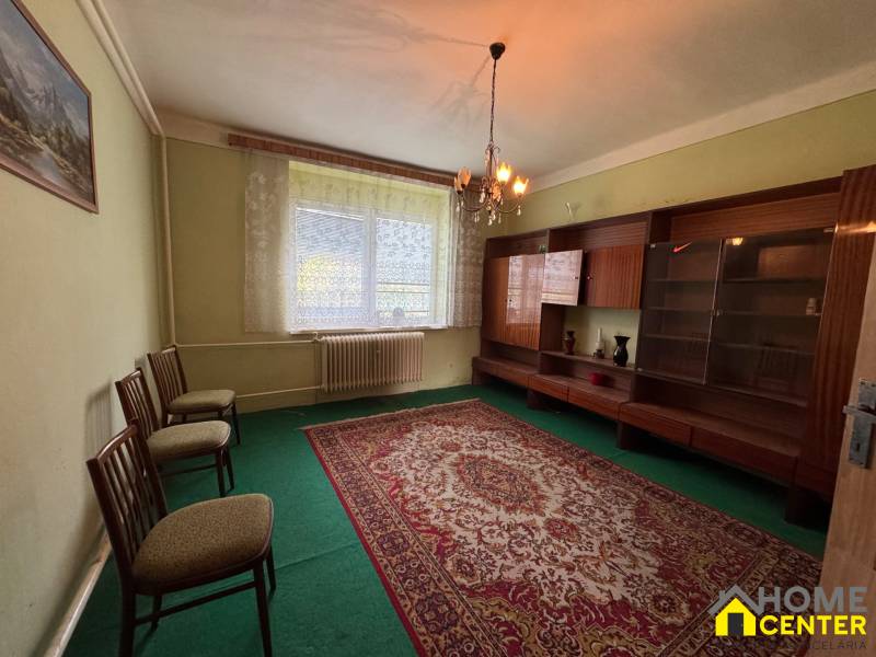 Wohnzimmer mit Teppich und Möbeln in einem Einfamilienhaus, sanft beleuchtet von einem Kronleuchter.