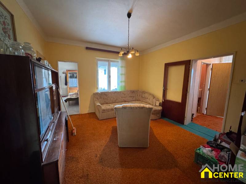 Wohnzimmer eines Einfamilienhauses mit älteren Möbeln, Sofa und Teppich.