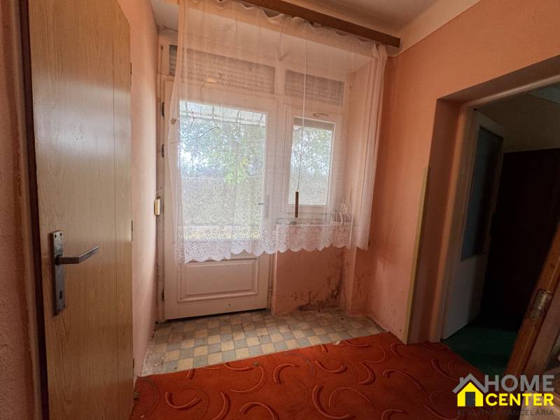 Innenraum eines Einfamilienhauses mit Türen und Vorhängen am Fenster, Boden mit kariertem Dekor.