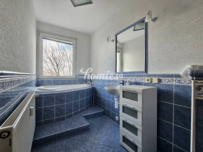 Ein Badezimmer mit blauen Fliesen und einer großen Badewanne in einer 3-Zimmer-Wohnung.