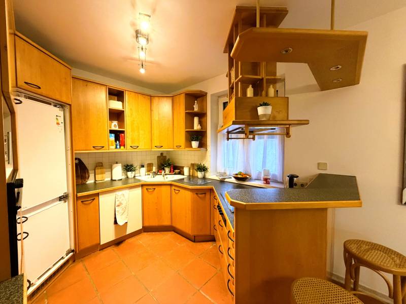 Küche in einer 3-Zimmer-Wohnung mit Holzschränken und Bartheke.