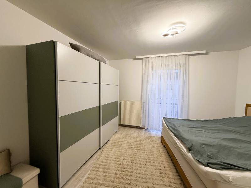 Schlafzimmer in einer 3-Zimmer-Wohnung mit Schrank, Bett und Boden mit Holzdekor.