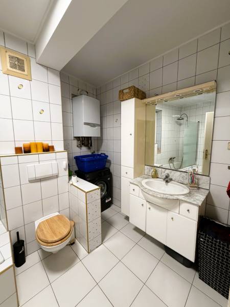 Badezimmer in einer 3-Zimmer-Wohnung mit weißen Fliesen, Waschmaschine und Waschbecken.
