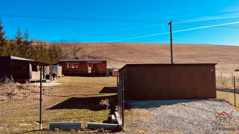 Baucontainer in der Straße Prosačov in Prosačov, umgeben von kleinen Bäumen und einem Zaun.