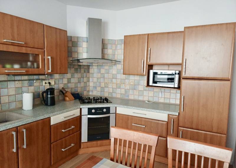 Küche in einer 3-Zimmer-Wohnung mit einer Holzküchenzeile und Fliesenverkleidung.