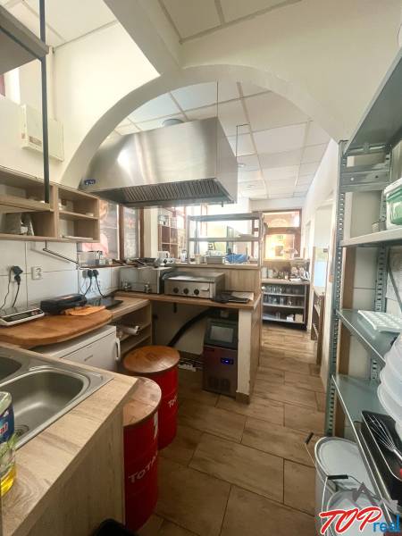 Gastronomiebereiche mit Holzdekor, Küchenzeile, Dunstabzugshaube, Elektrogeräte, Regale, Stühle.