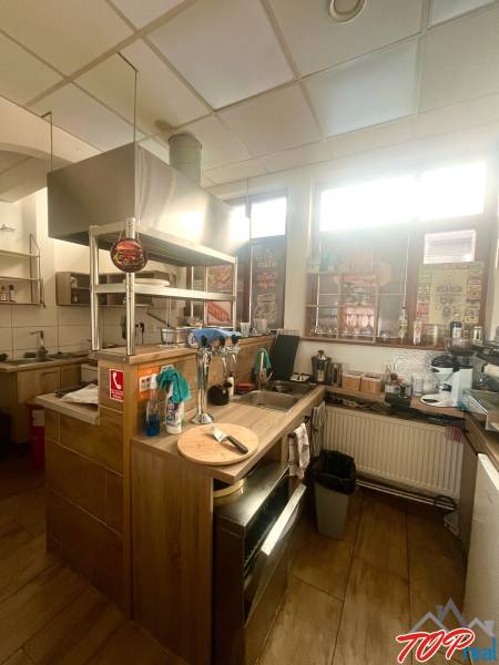 Eine Küche in gastronomischen Räumlichkeiten mit einem Boden in Holzoptik, ausgestattet mit modernen Geräten.