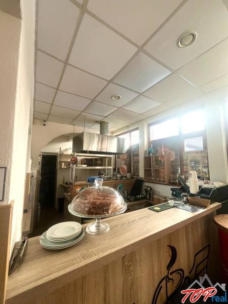 Innenraum eines Gastronomiebereichs mit Holzboden, Tresen, Gebäck und Tellern.