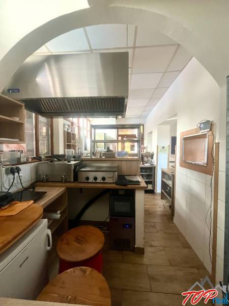 Küchenbereich mit Edelstahl-Dunstabzugshaube und Holzboden in Gastronomiebereichen.