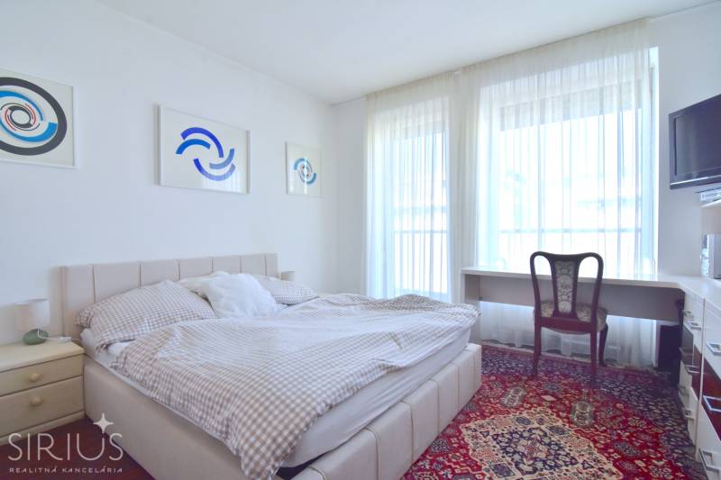 Schlafzimmer in einer 3-Zimmer-Wohnung mit Bett, Tisch und Kunstwerken an der Wand.