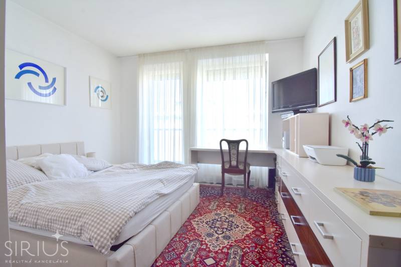 Helles Schlafzimmer mit Sessel, Bett und Teppich in einer 3-Zimmer-Wohnung.