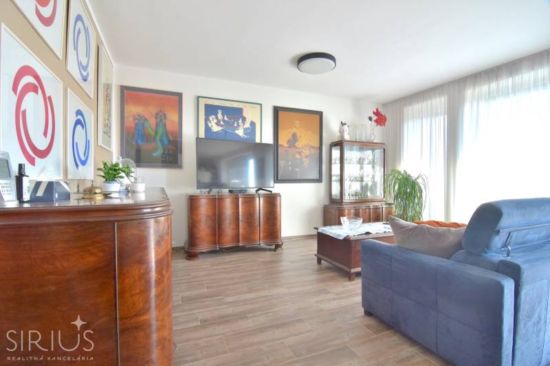 Wohnzimmer mit dunklen Möbeln, Holzboden und dekorativen Bildern in einer 3-Zimmer-Wohnung.