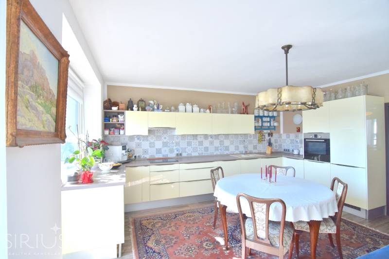 Küche in einer 3-Zimmer-Wohnung mit Holzmöbeln, Blumen und gemustertem Teppich.