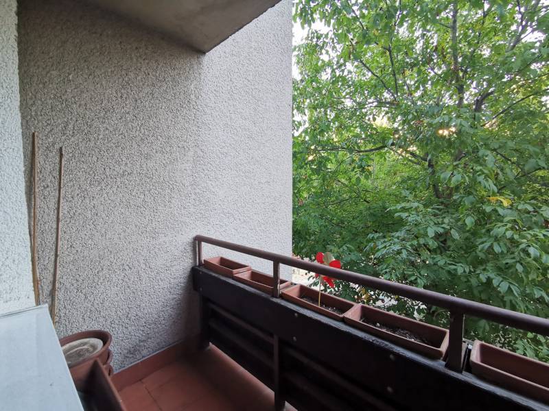 Ein Balkon in einer 4-Zimmer-Wohnung, umgeben von Grün mit Blumenkästen am Geländer.