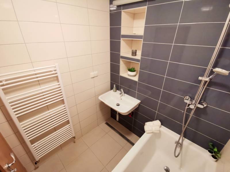 Badezimmer in einer 4-Zimmer-Wohnung mit Badewanne, Waschbecken und Ablagefächern.