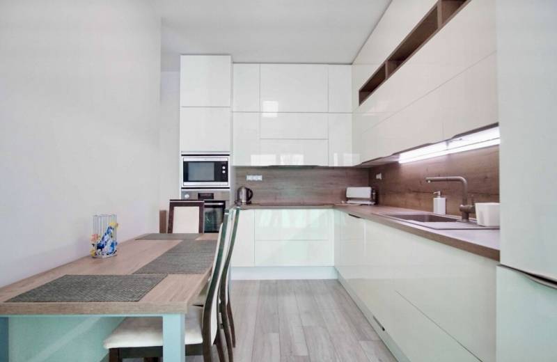 Küche in einer 3-Zimmer-Wohnung mit Holzboden und hellen Möbeln.