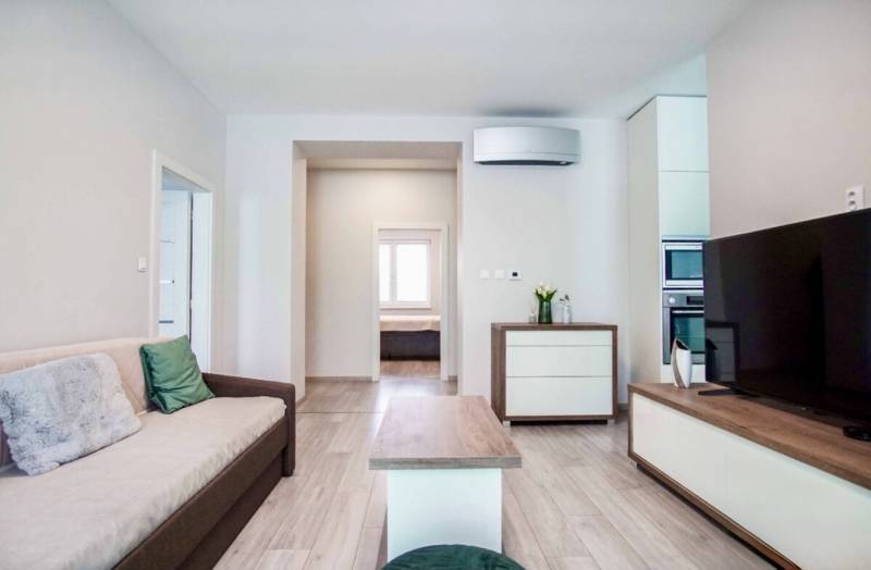 Wohnzimmer in einer 3-Zimmer-Wohnung mit Holzboden und bequemer Couch.