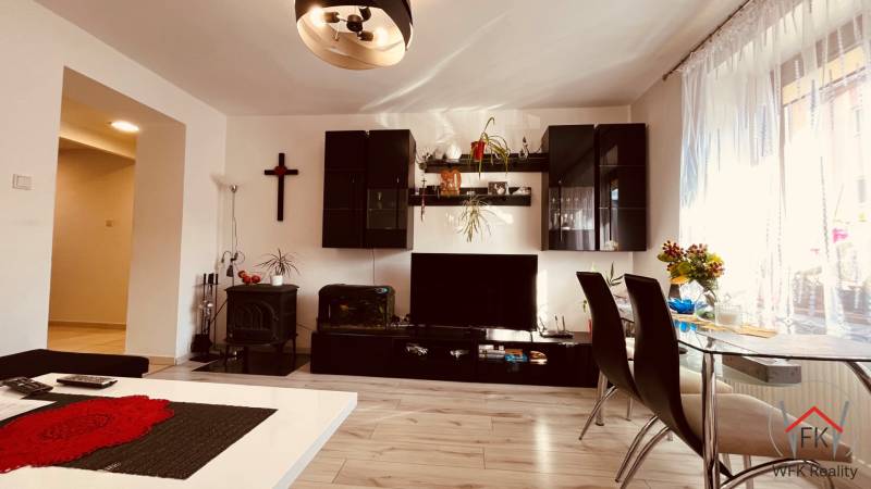 Wohnzimmer einer 3-Zimmer-Wohnung mit Holzboden, Esstisch und Wandregal.