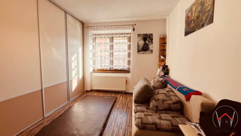 Ein Zimmer in einer 3-Zimmer-Wohnung mit einem Boden in Holzoptik, einem Sofa und einem Einbauschrank.