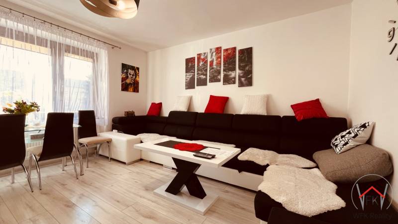 Wohnzimmer in einer 3-Zimmer-Wohnung, mit einem Sofa und einem Boden in Holzoptik.