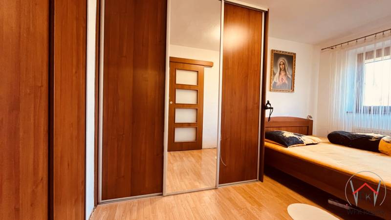 Schlafzimmer in einer 3-Zimmer-Wohnung mit Holzboden, Kleiderschrank und Bild.