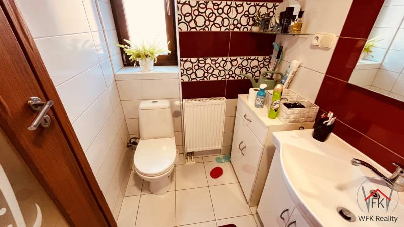Badezimmer mit Toilette in einer 3-Zimmer-Wohnung, enthält weiße Sanitäreinrichtungen und dekorative Fliesen.