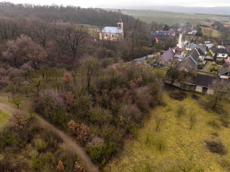Gemerské Teplice erfassen Erholungsgrundstücke mit waldreicher Landschaft und einer Kirche im Hintergrund.