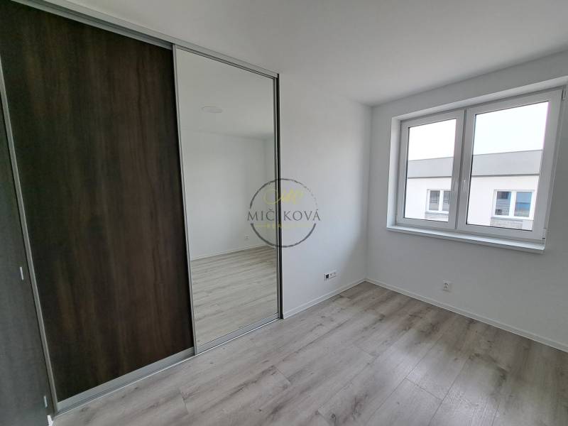 Ein Zimmer in einem Einfamilienhaus mit einem Boden in Holzoptik und einem großen Spiegelschrank.