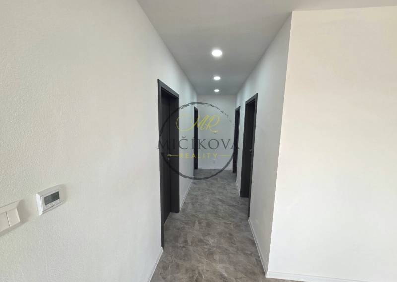 Flur in einem Einfamilienhaus mit dunklen Türen und Bodenbeleuchtung in Holzoptik.