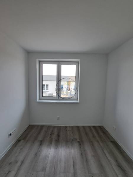 Ein Zimmer in einem Einfamilienhaus mit einem Holzboden und einem großen Fenster.